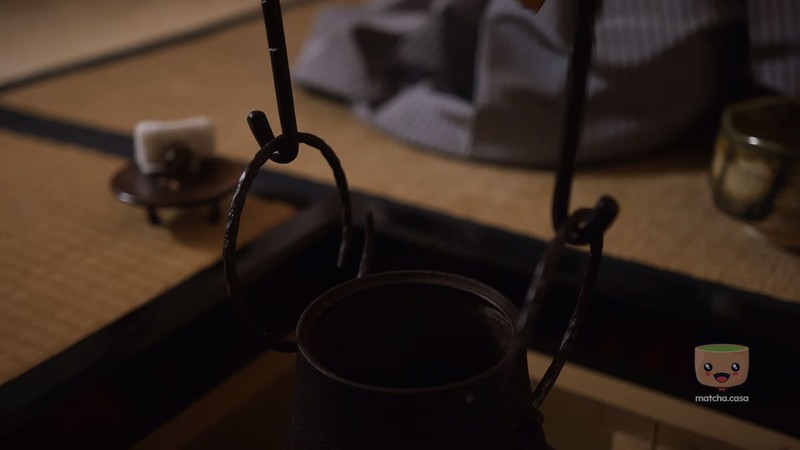 un homme qui met de l'eau dans un bol de matcha