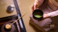 un homme dans une cérémonie du thé, qui met de l'eau bouillante dans un bol de matcha 