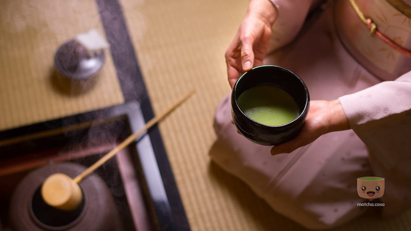 une femme en tenue traditionnelle japonaise qui tient un bol de matcha